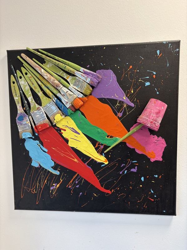 Pinsel mit bunter Farbe auf schwarzem quadratischen Untergrund