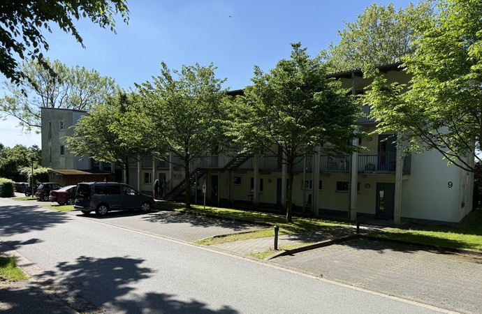 Großes Haus hinter Bäumen an einer Straße