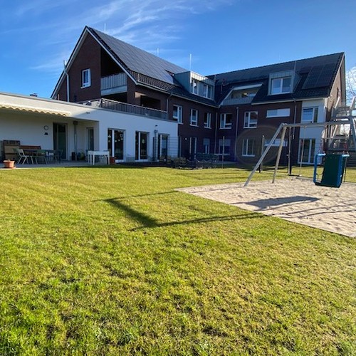 Modernes Haus auf grüner Wiese unter blauem Himmel